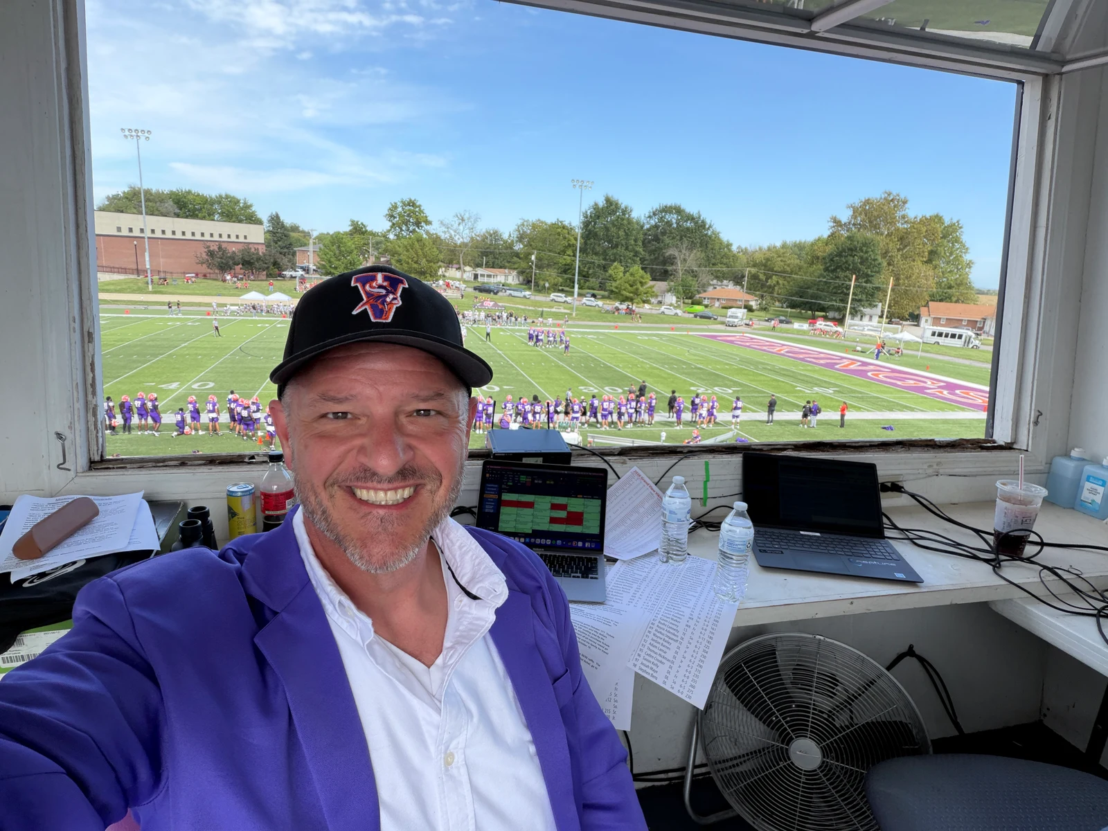 Chris Kamler smiling in a stadium announcing booth