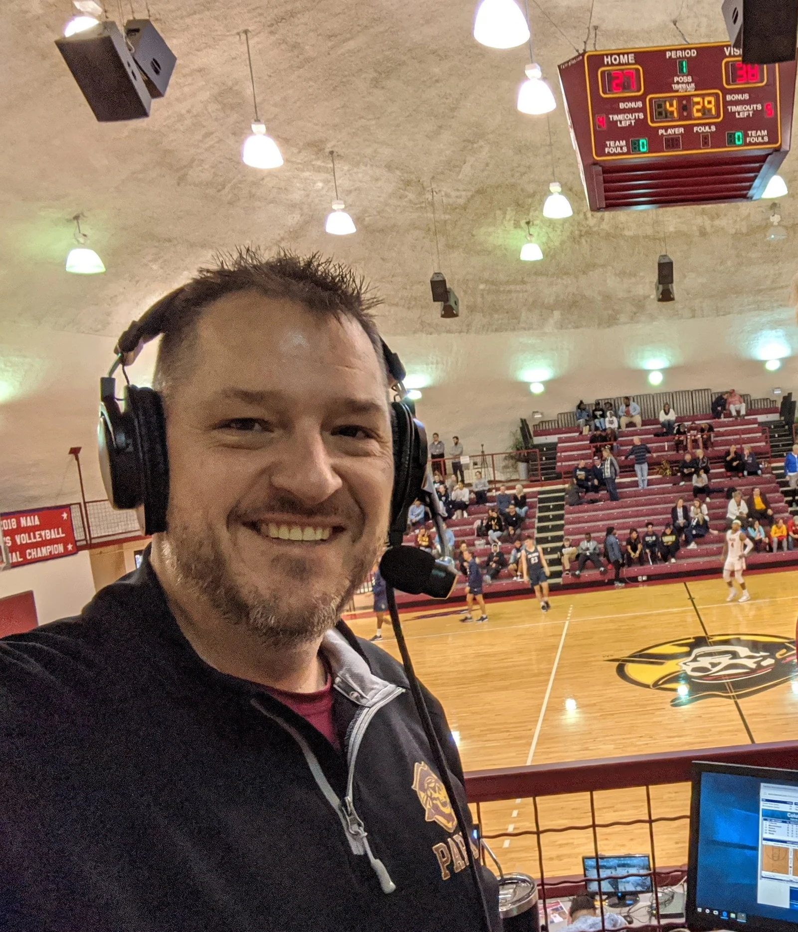 Chris Kamler wearing a headset overlooking a basketball court